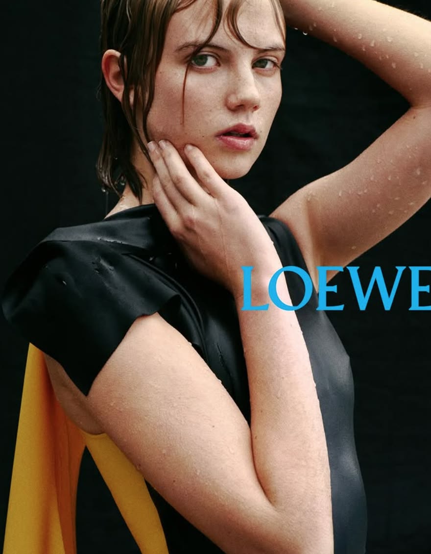 Wet-haired model with hand to cheek against black